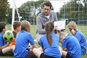 — title missing — A soccer coach teaching children.