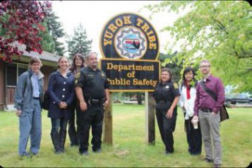 — title missing — A group of people stand near the sign for the Yurok tribe.
