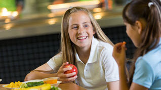 Girls eating at table Two students eating lunch.