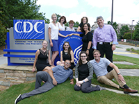 ryan-lacson A teacher and students pose around a CDC sign on a grassy hill.