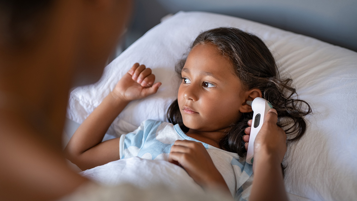 — title missing — Mother checking daughter temperature with an ear thermometer.