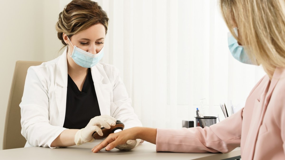 Doctor Checks Skin a doctor examining a mole on a woman's hand