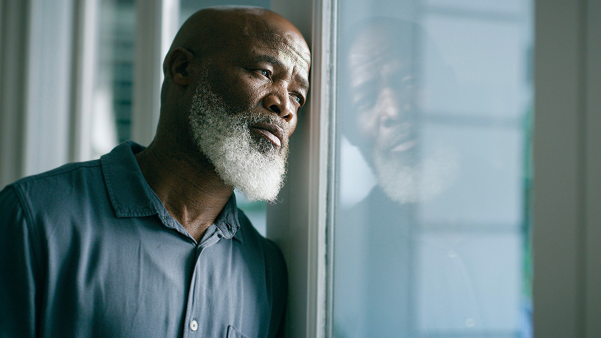 Lonely Senior Man in Window Senior man looking out the window.