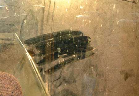 full200203c Foto 3: Esta foto muestra la vista a través de la ventana trasera desde el asiento del conductor de la motoniveladora. Parte del polvo se limpió, y si se mira cuidadosamente a través de la neblina, uno apenas puede ver a una persona parada a varios pies de distancia de la motoniveladora.