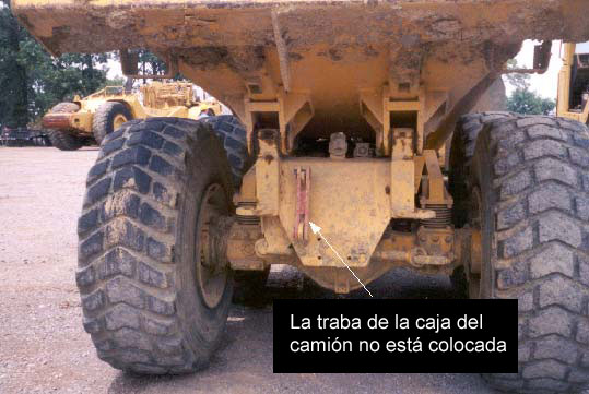 full200208e Esta fotografía fue tomada desde detrás del camión. La flecha señala la traba de la caja del camión y muestra la posición de la traba cuando la caja del camión no está elevada y la traba no está colocada.