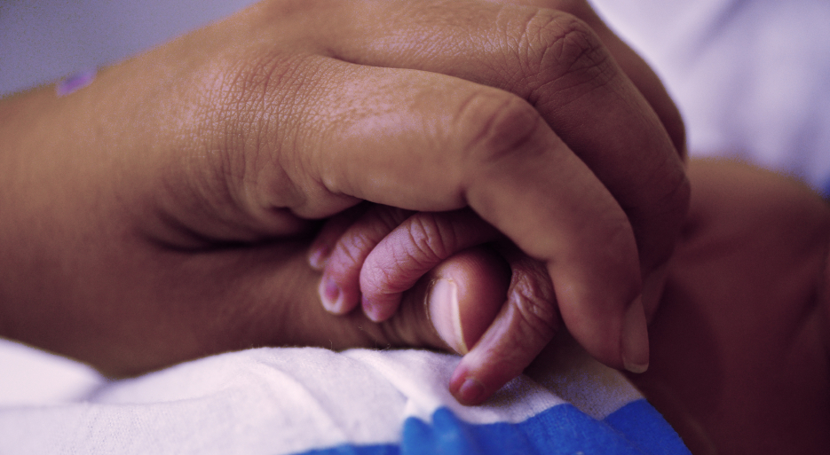 Newborn hand with adult hand adult hand holds infant hand