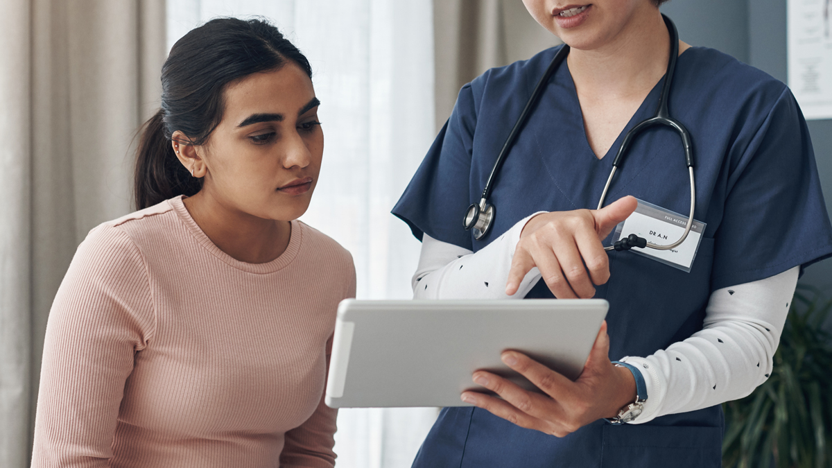 patient with doctor - screening a young woman looking at a screen with her healthcare provider