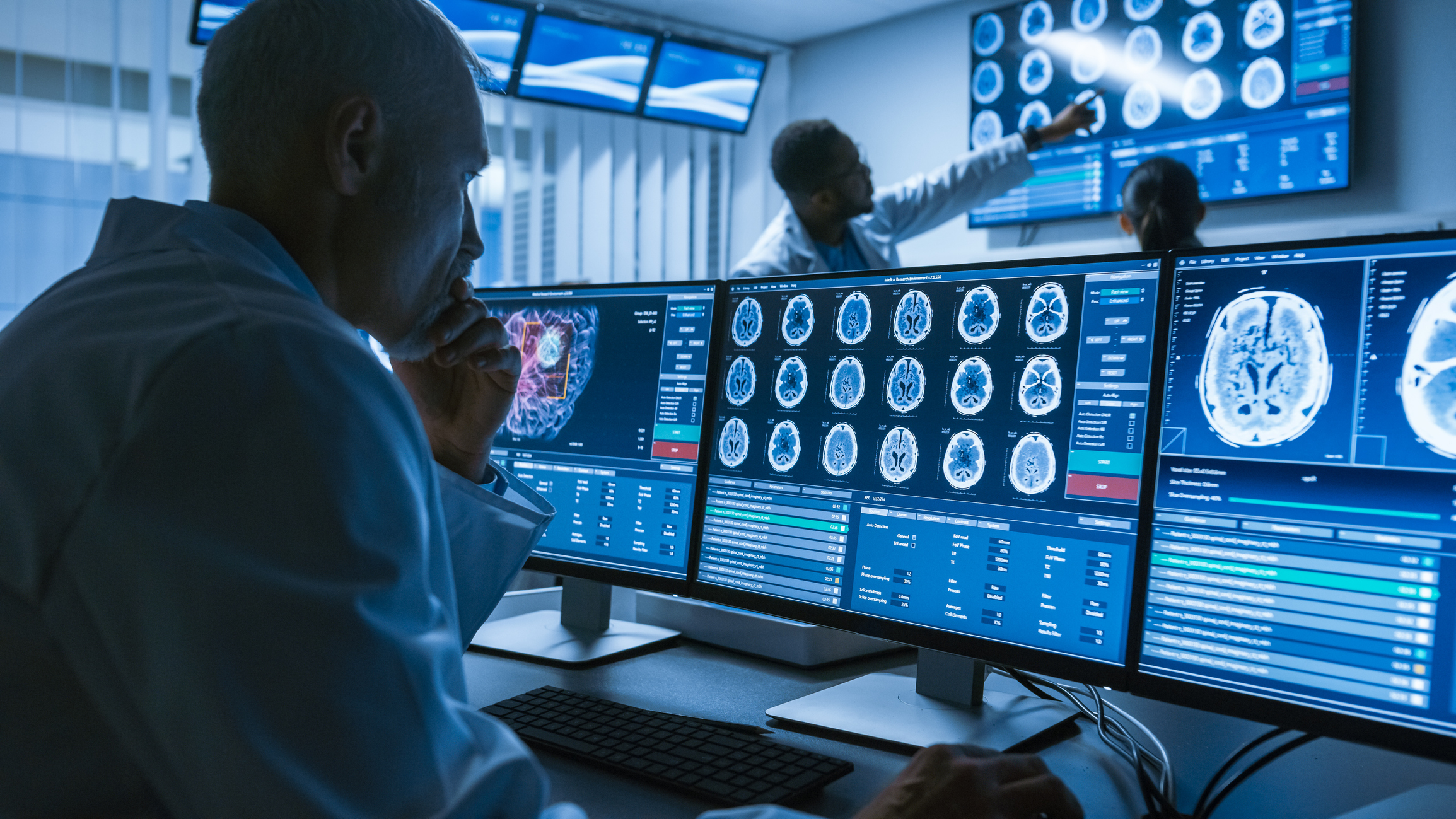 Over the Shoulder Shot of Senior Medical Scientist Working w… Over the Shoulder Shot of Senior Medical Scientist looking at brain scans.