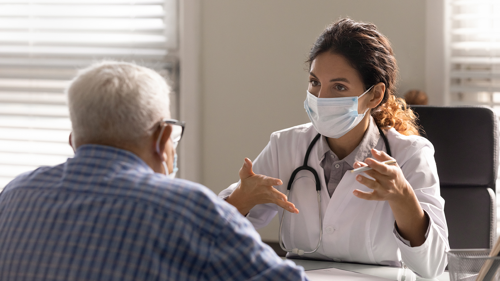 Close up female therapist wearing face mask consulting mature patient Close up female therapist wearing face mask consulting older patient