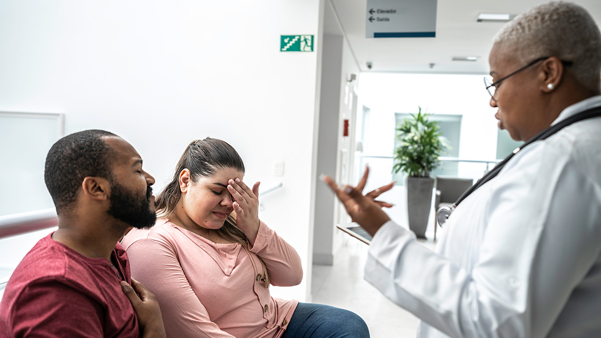 Grieving couple Female doctor talking to grieving couple in a hospital