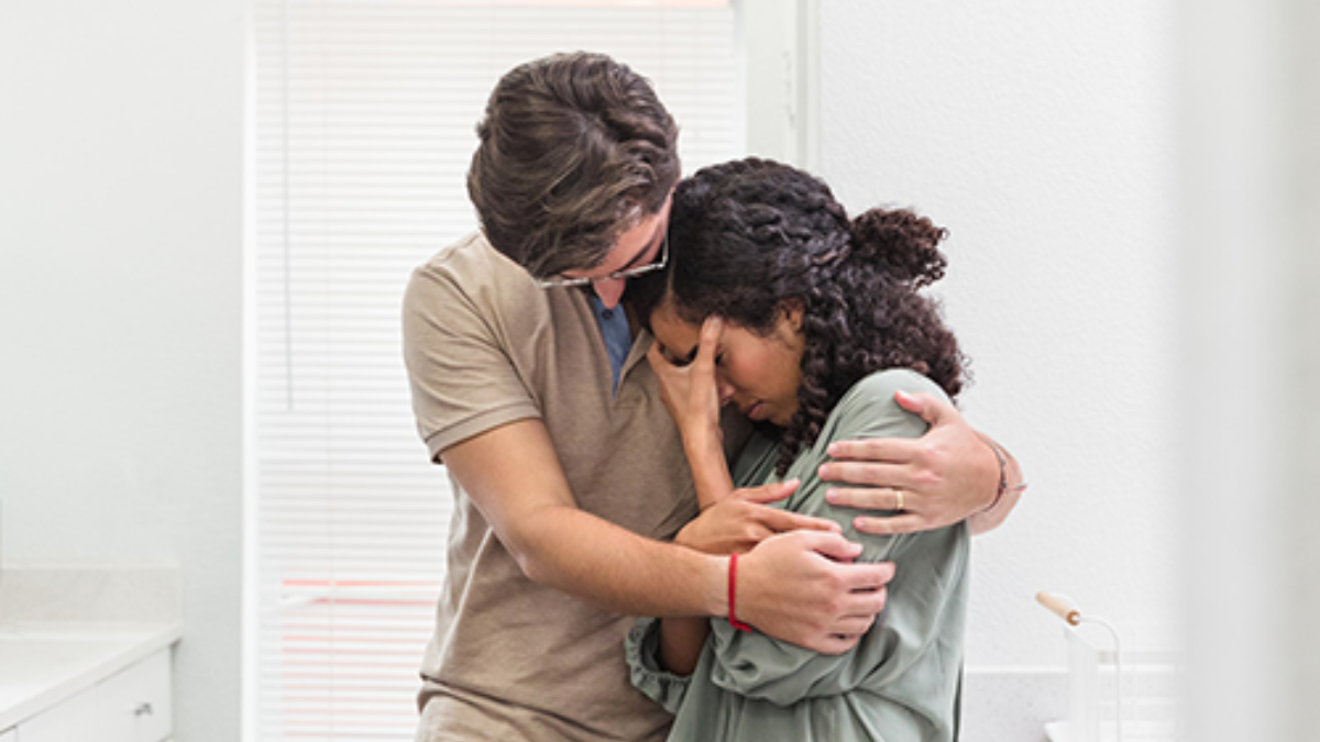 Sad couple hugging Young man hugs crying young woman