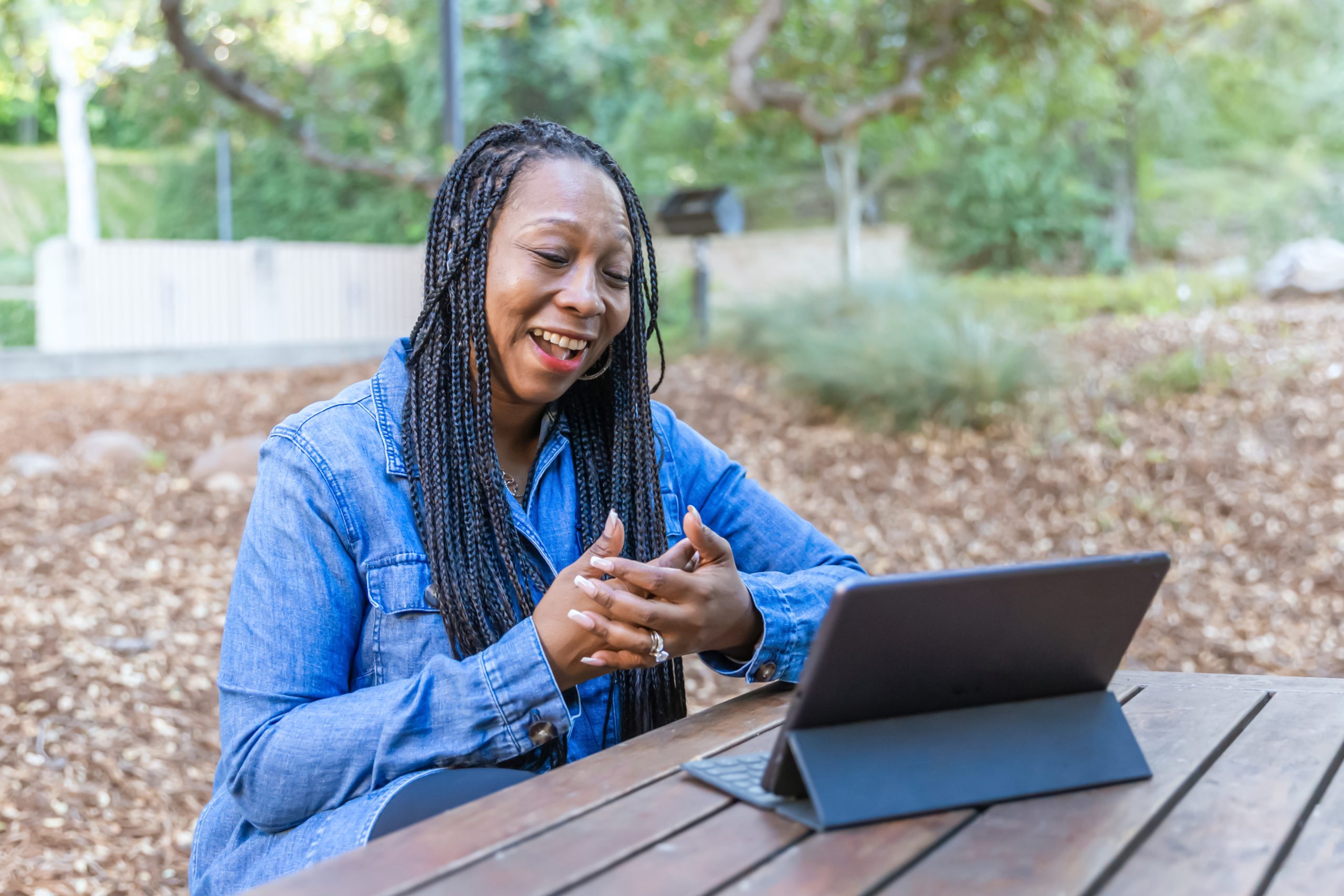 Woman on tablet A woman having a conversations with someone virtually on a tablet outside in a park.