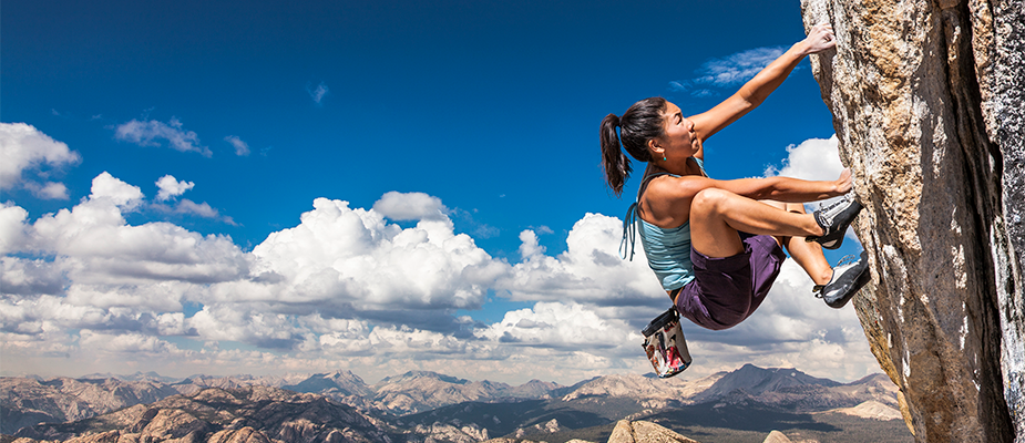 woman climbing an outdoor rock wall woman climbing an outdoor rock wall with sky and mountains in the background