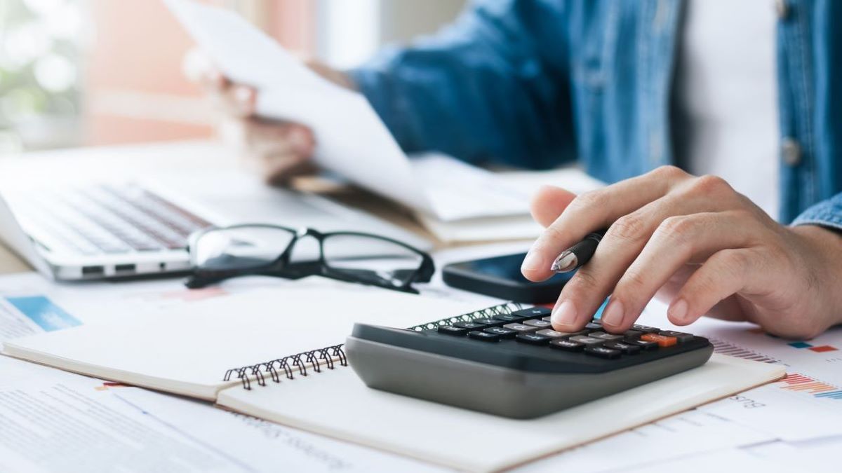 Male calculator desk 1200x675px Male using a calculator at his desk.