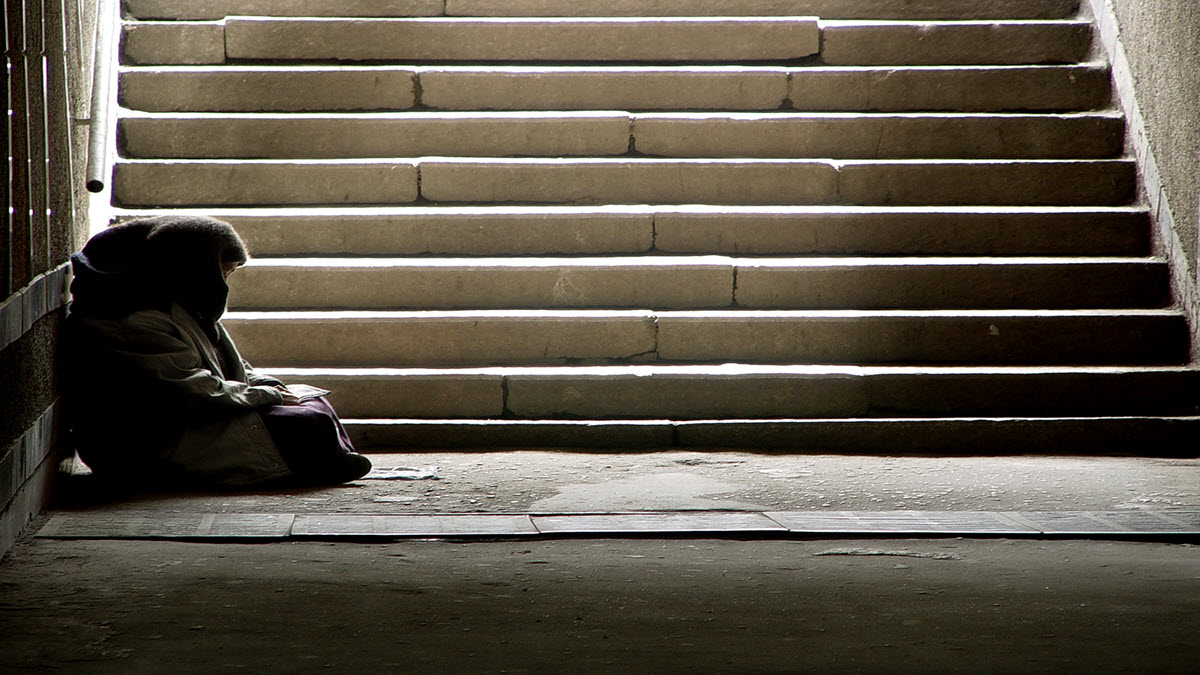 A person experiencing homelessness A person experiencing homelessness sitting at the bottom of a staircase
