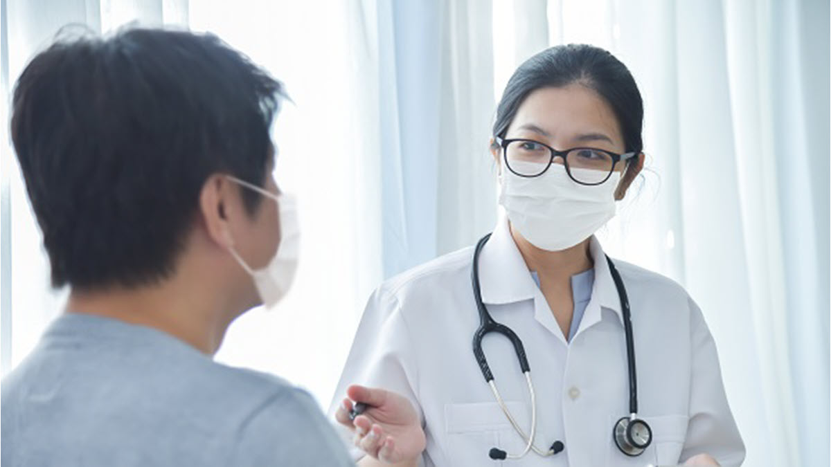 Doctor talking to patient Female doctor talking to a male patient and both are wearing masks