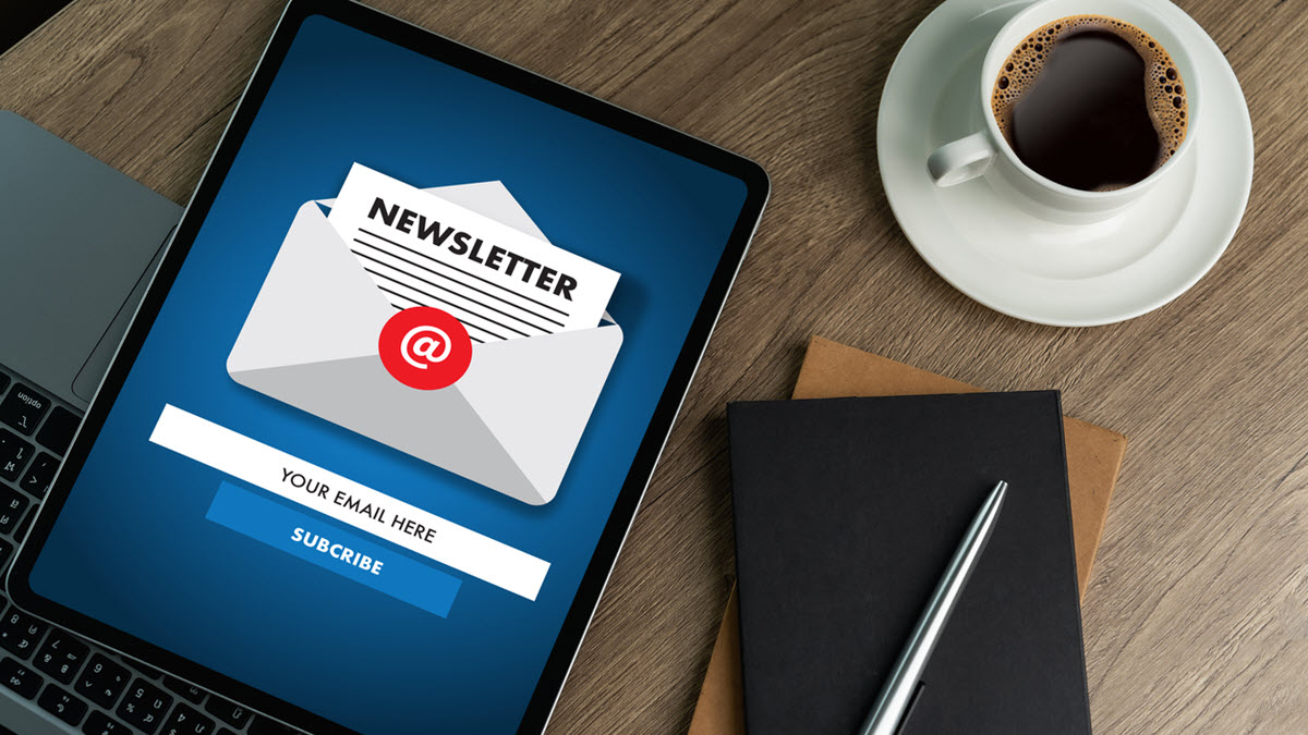 Newsletter_on_Tablet A digital newsletter is shown on an electronic tablet next to a notepad and cup of coffee.