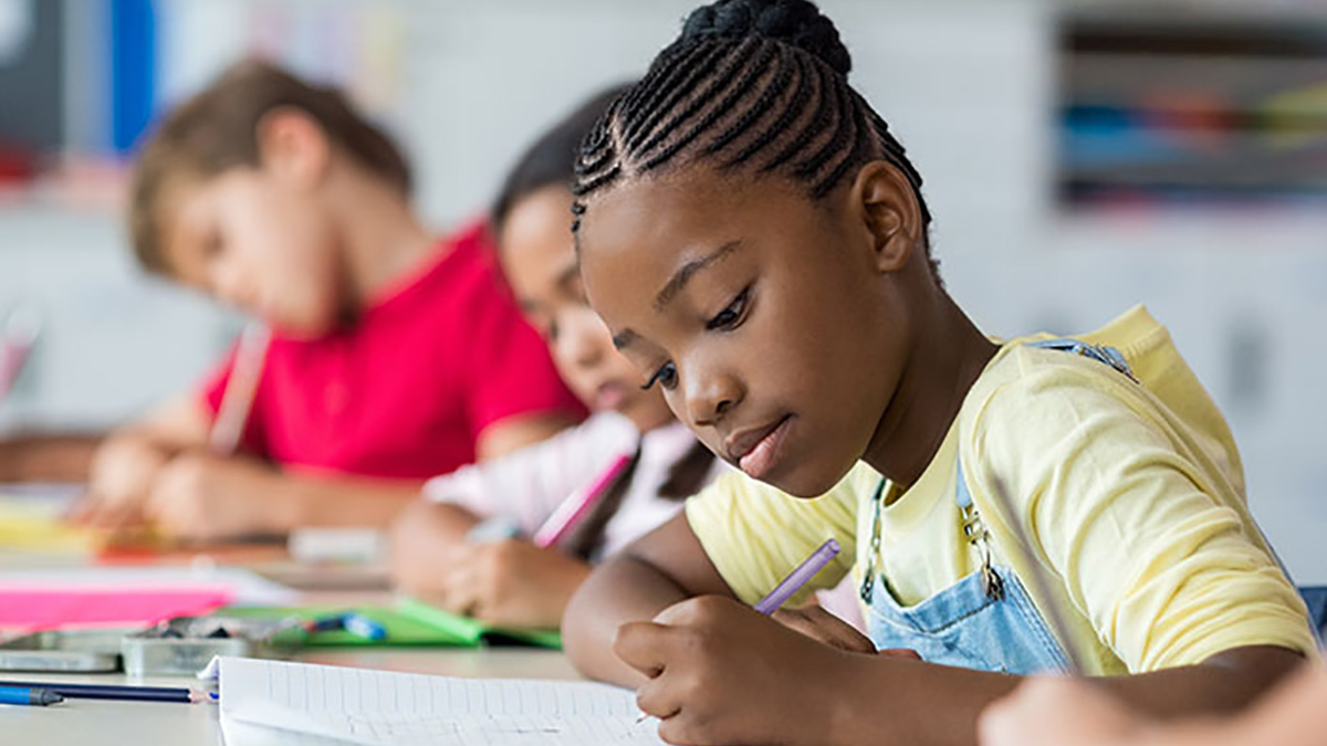 Young Student Writing Young students sit writing at their desks.