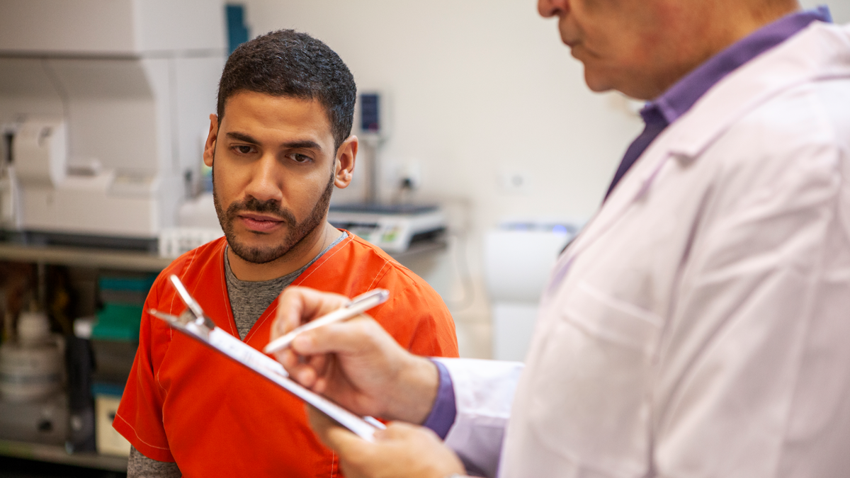 — title missing — Man in correctional facility getting information from doctor