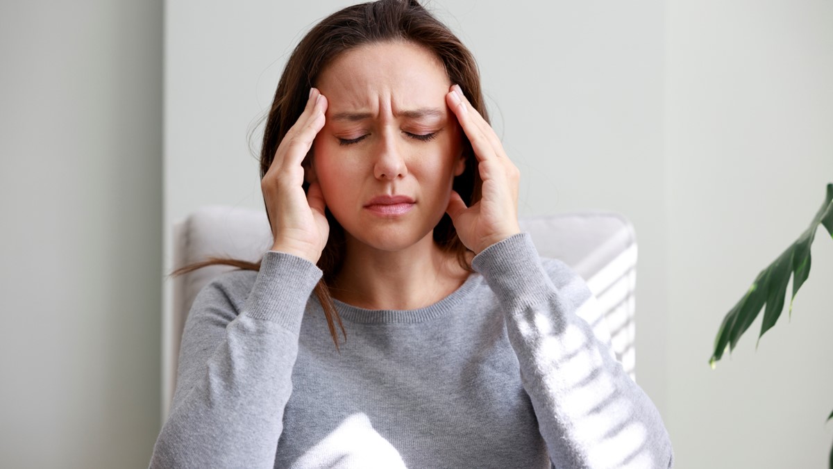 Woman with headache and closed eyes A woman holds her head and closes her eyes in pain.