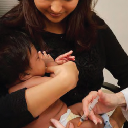 Mom holding infant receiving vaccine Mom with baby getting vaccinated