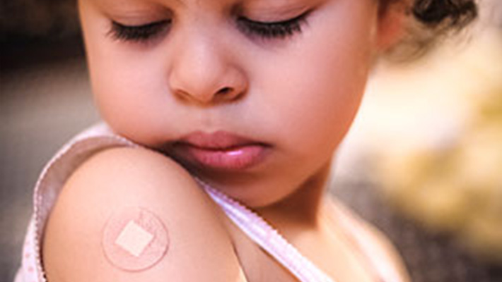 Little girl with band-aid on arm A little girl looking at the band-aid on her right shoulder from where she got a vaccine.