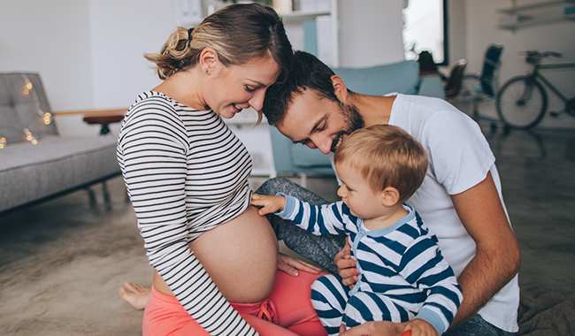 Father and mother hold young child touching pregnant belly for vaccine protection