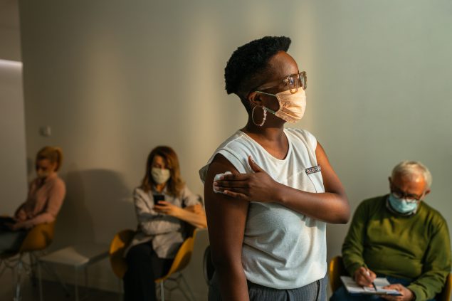 Vaccinated woman in hospital A vaccinated woman stands in a hospital waiting room.