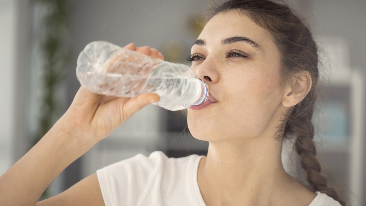Drinking bottled water Woman drinking bottled water inside