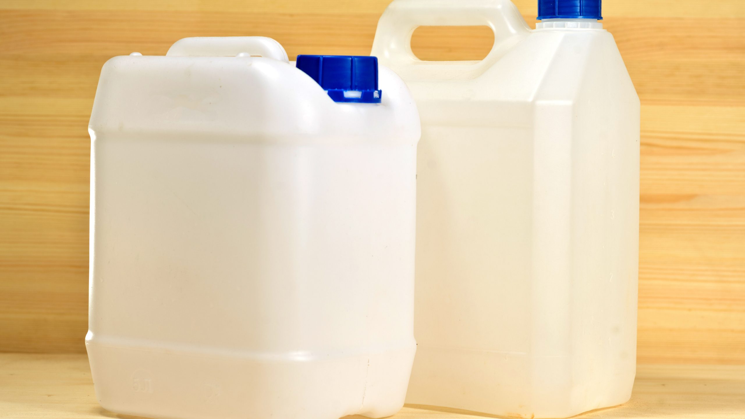plastic gallon containers Picture of white plastic gallon containers on the background of wooden wall