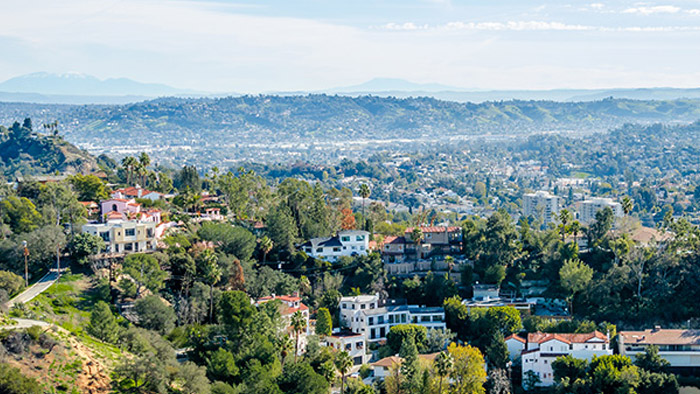 wildfire before Aerial view of a tree-filled community on a clear, sunny day.
