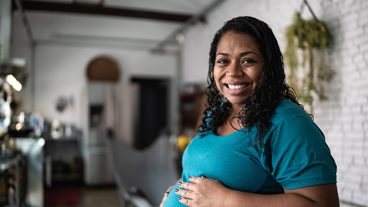 pregnant woman Pregnant woman in her home and smiling at the camera.
