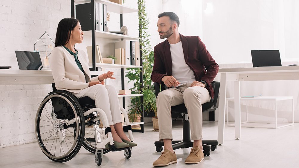 woman wheelchair office woman in wheelchair in a discussion with co-worker