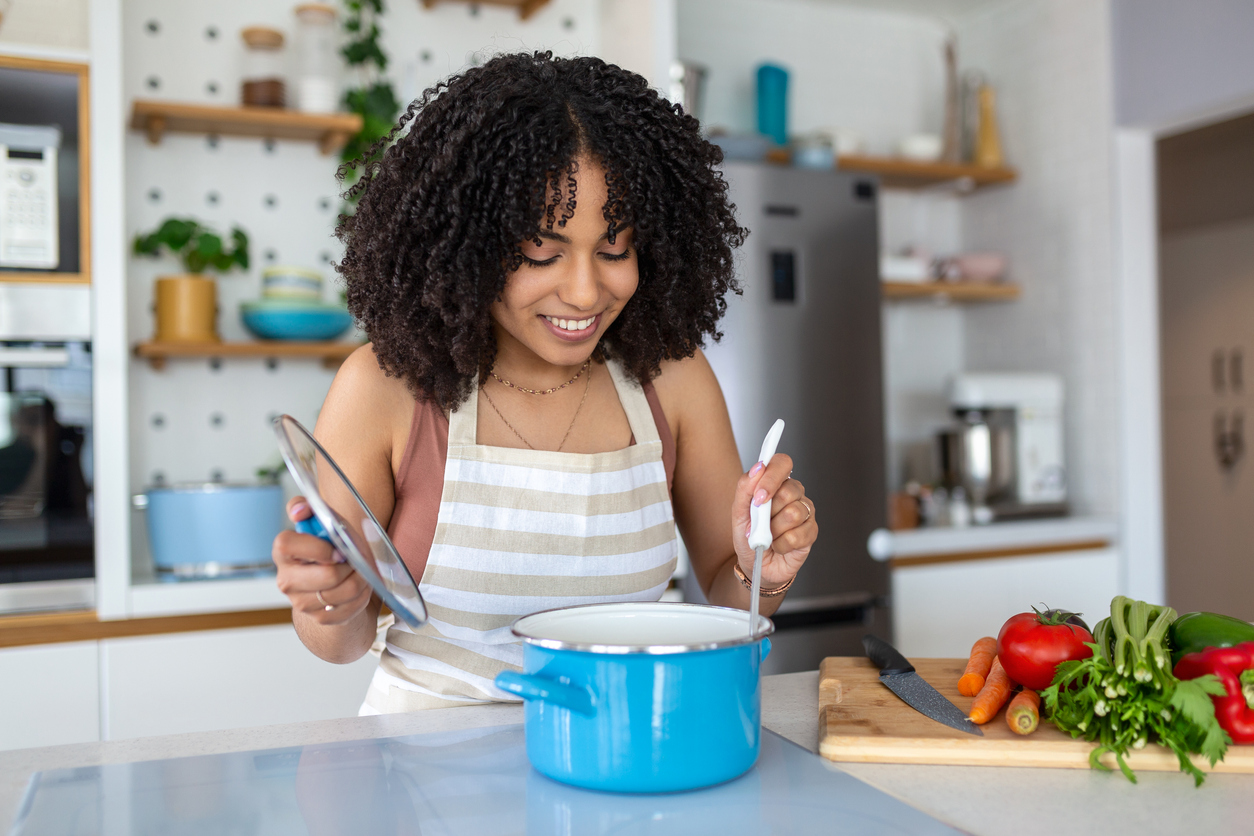 Girl cooks food in kitchen A young woman with curly hair cooking in a kitchen.