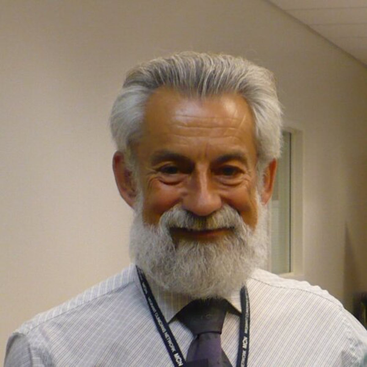 Ed Zuroweste 2024 TB Champion Dr. Ed Zuroweste smiling, wearing a button up and blue tie, with grey hair and beard