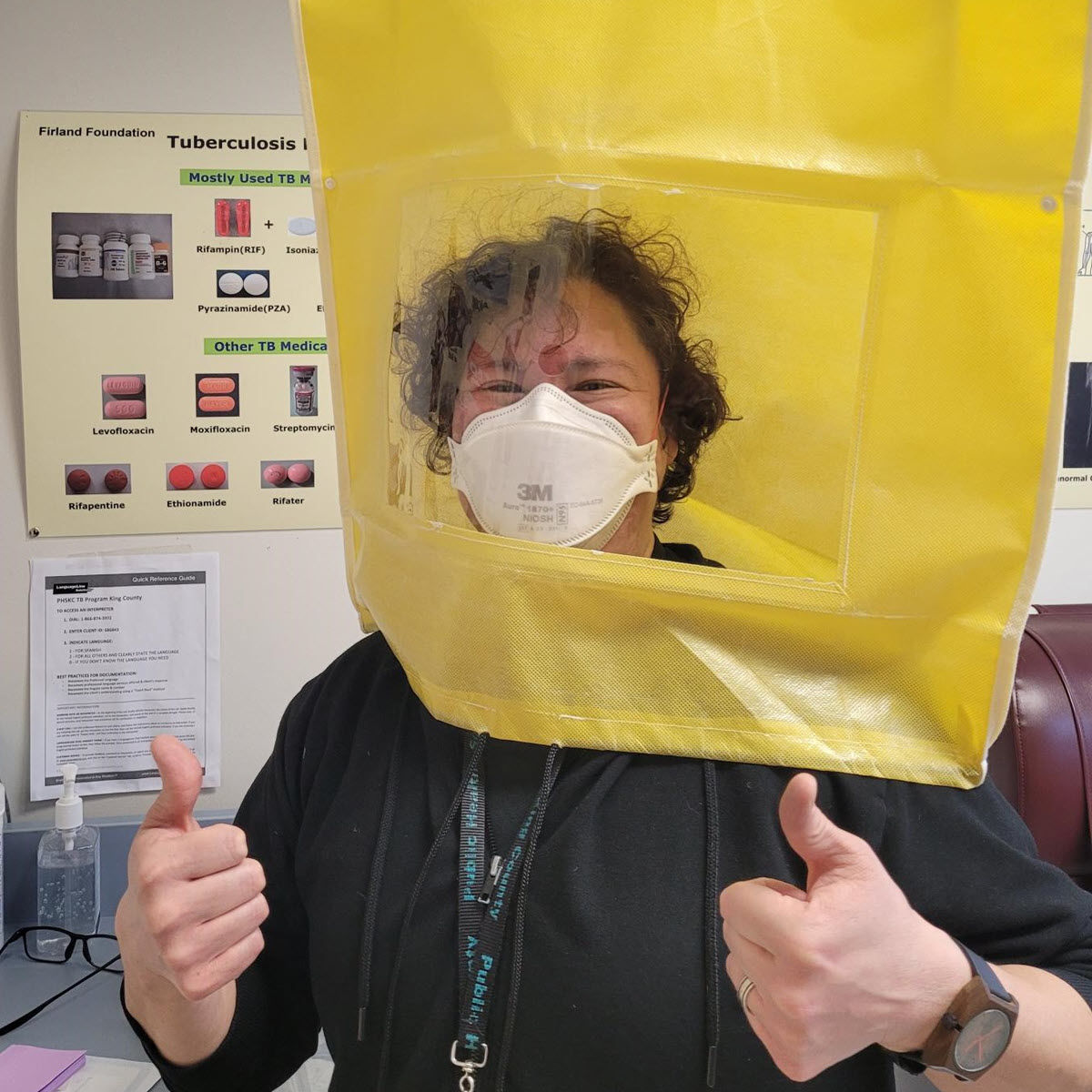 Moni Muraki Moni Muraki wearing PPE in a clinical setting with their thumbs up wearing a black shirt