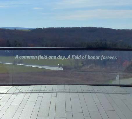 A poignant view of the Flight 93 Memorial's Flight path overlook, featuring a glass barrier inscribed with the powerful quote "e; A common field one day. A field of honor forever."e; The scene pays tribute and stands as lasting symbol of honor and remembrance.