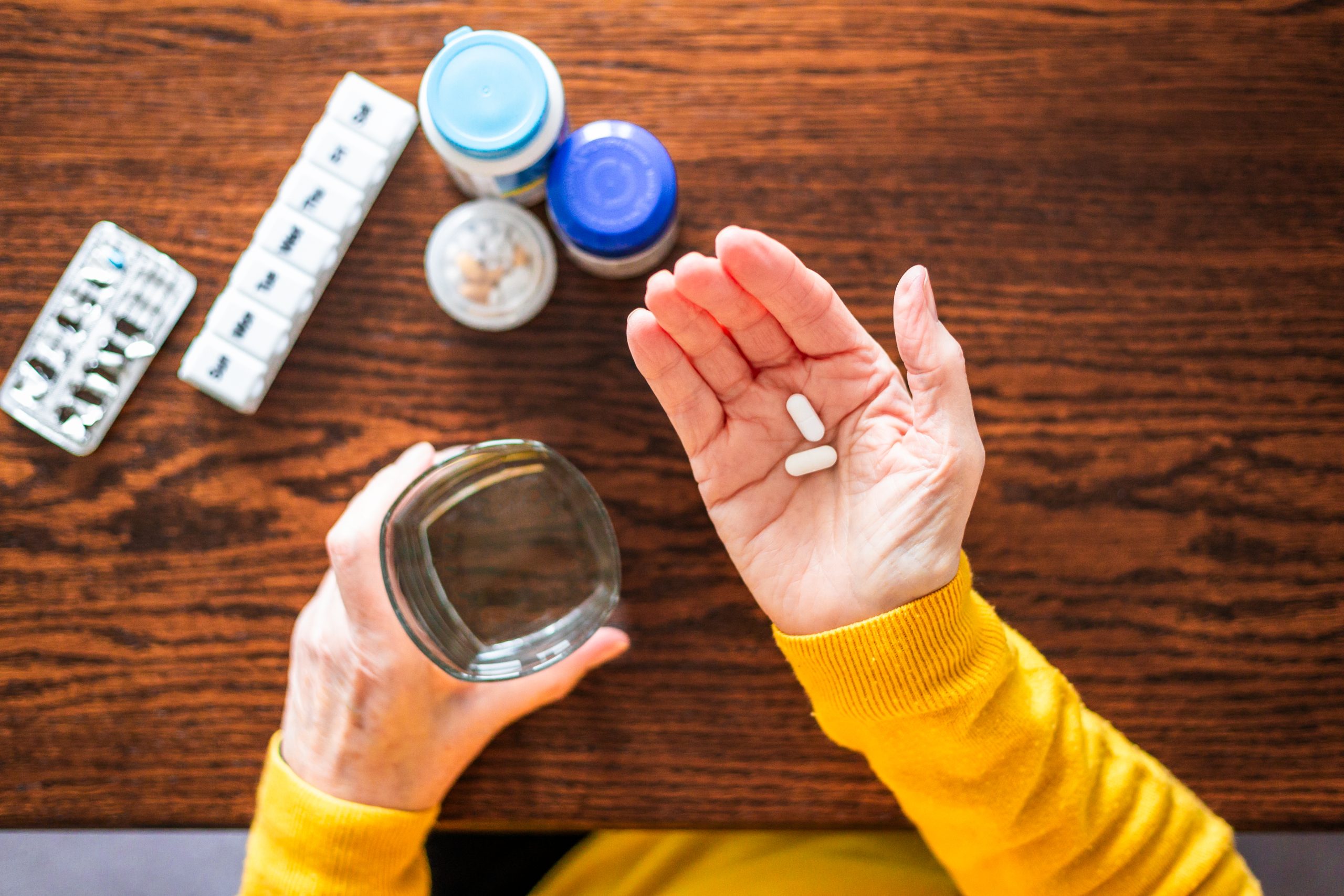Traveler has medication in one hand and water in other hand.