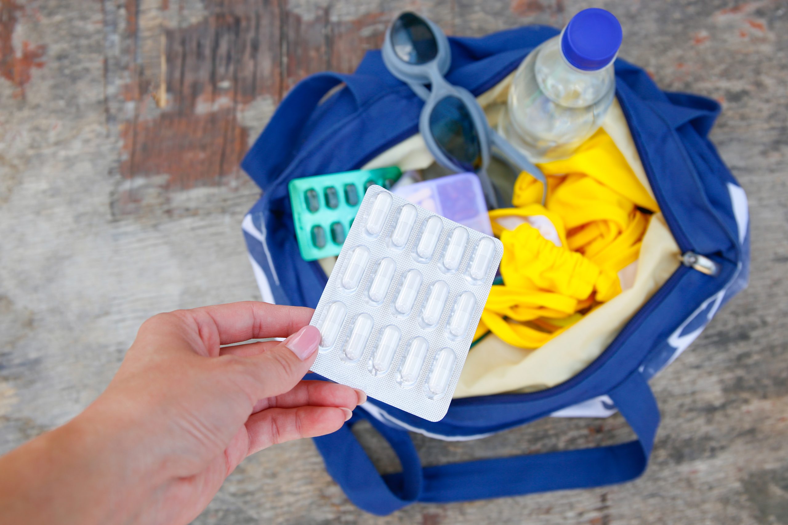 Traveler holds a packet of medication from a travel health kit.