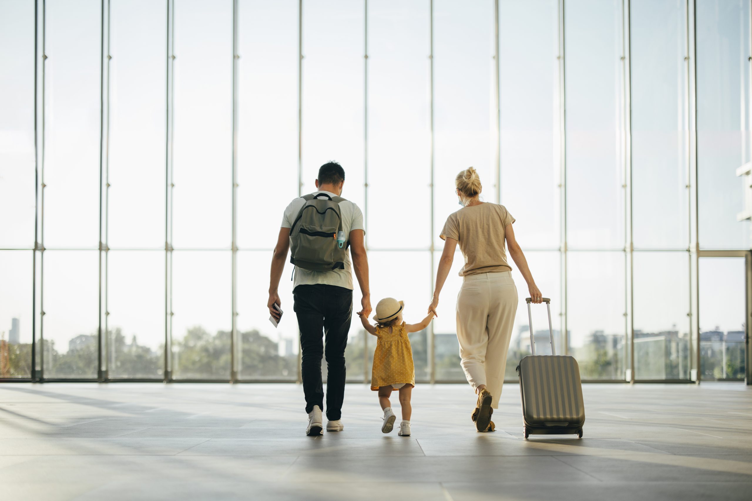 Family walking together and holding hands in an airport.