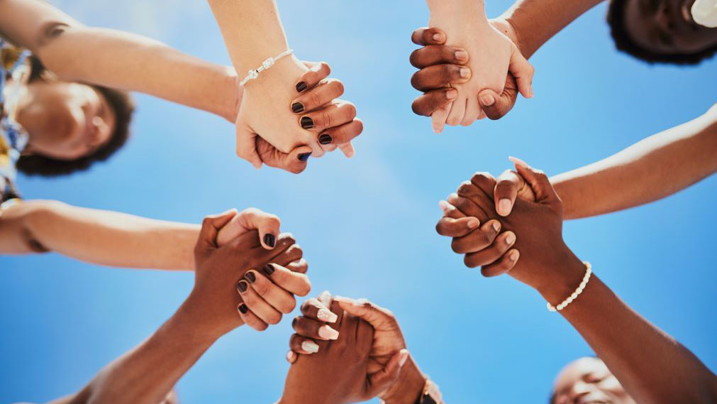 Group of teens success stories A diverse set of young people with outstretched arms, holding hands.