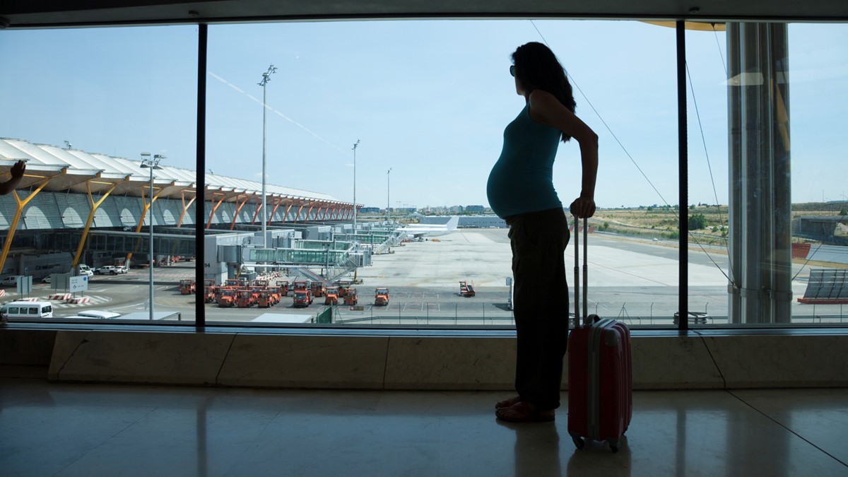 Pregnant woman at airport A pregnant woman looks out of the window at an airport.